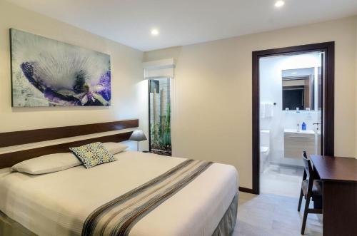 a bedroom with a bed and a desk and a bathroom at Isla Verde Hotel in San José