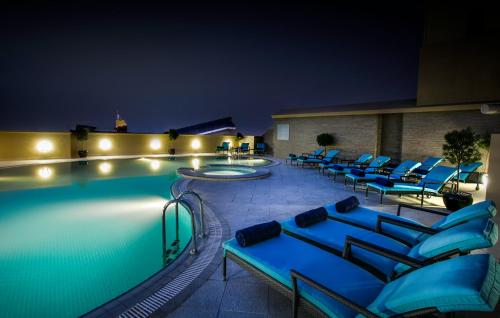 a swimming pool with blue lounge chairs next to it at Elite Byblos Hotel in Dubai