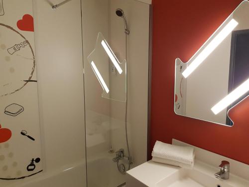 a bathroom with a shower and a sink and a mirror at Ibis Budget Saint Christol Les Alès in Saint-Christol-lès-Alès