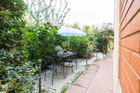 una mesa y sillas con una sombrilla en el jardín en Casa Francesco, en Bolsena