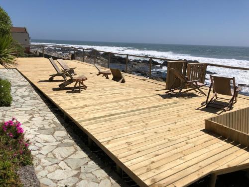 a wooden deck with chairs and the beach at Delfín Apart in Pichilemu