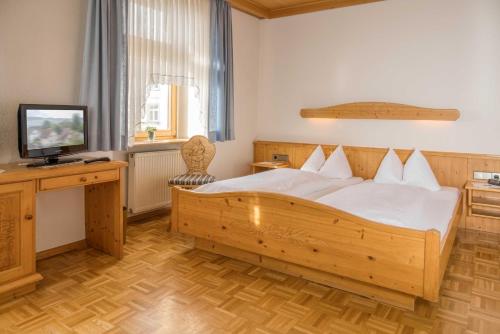 a bedroom with a wooden bed and a television at Gasthaus Kranz Bonndorf in Bonndorf im Schwarzwald