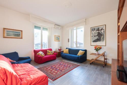 a living room with blue and red furniture and windows at Cappuccini Florence Family & Group 3 Bedrooms Jacuzzi Fast Wi-Fi Air Conditioned Tram in Florence