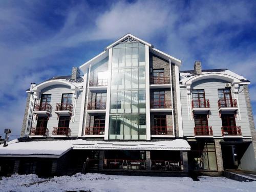 een groot wit gebouw met glazen ramen in de sneeuw bij Three Penguins in Bakuriani