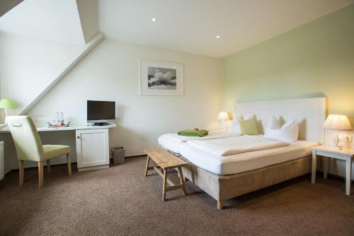 a bedroom with a bed and a desk with a computer at Paulsen's Landhotel und Restaurant in Bohmstedt