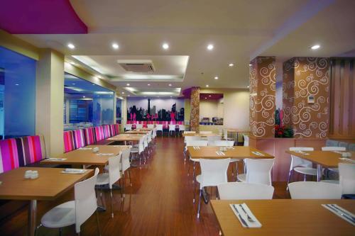 un ristorante con tavoli in legno e sedie bianche di favehotel Kelapa Gading a Giacarta