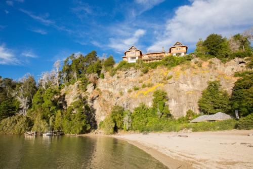 a house on top of a hill next to a body of water at Hostería Isla Victoria Lodge in Isla Victoria