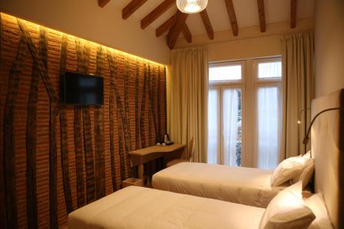 a hotel room with two beds and a television at Muralha Charm House in Lamego