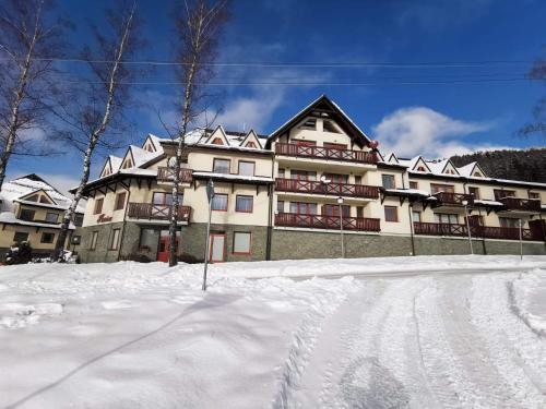 a large building with snow in front of it at Apartmán Plesnivec in Donovaly