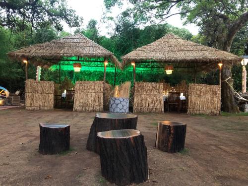 two huts with tree stumps in front of them at Evershine Resort & Spa in Mahabaleshwar