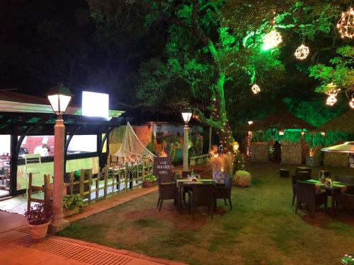 a restaurant with tables and chairs under a tree at night at Evershine Resort & Spa in Mahabaleshwar