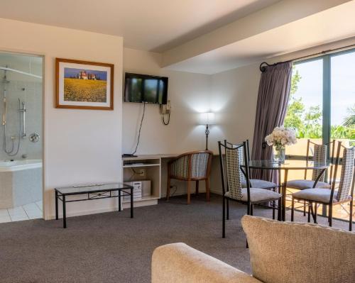 a living room with a tub and a table and chairs at Tuscany Gardens Motor Lodge in Nelson