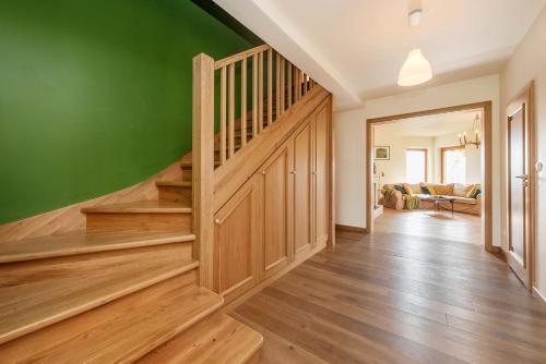 a living room with a green wall and wooden stairs at Dom w Grodzisku in Skała