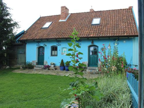 a blue house with a red roof and a yard at Pod tulipanem nad jeziorem in Zawady Oleckie