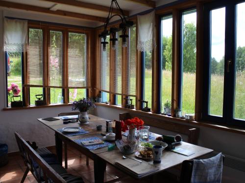 uma sala de jantar com uma mesa e um monte de janelas em Pod tulipanem nad jeziorem em Zawady