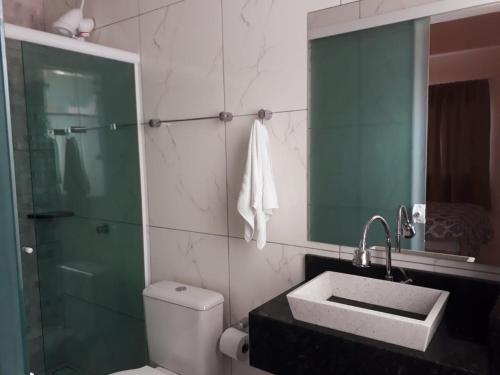 a bathroom with a toilet and a sink and a shower at Marlindo Hospedagem in Penha