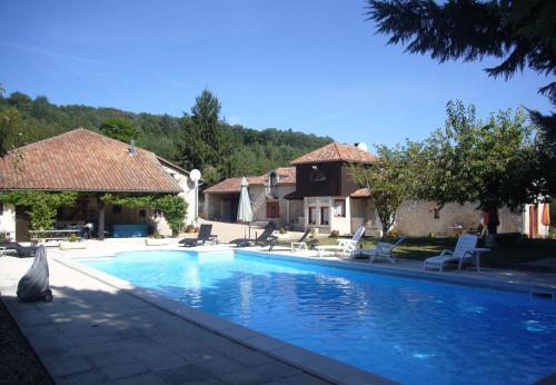 a swimming pool with chairs and a house at Les Gîtes de La Treille in Montagrier