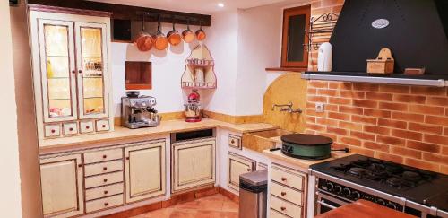 a kitchen with white cabinets and a brick wall at La Bergerie de Louvie in Louvie-Soubiron