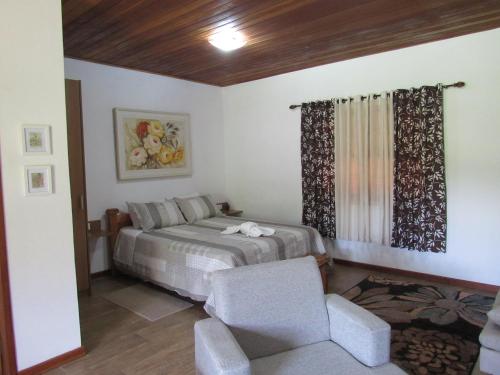 a bedroom with a bed and a chair in it at Chalés Luar da Serra in Santo Antônio do Pinhal