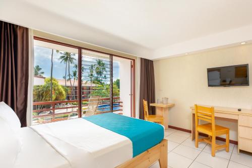 a hotel room with a bed and a desk and a balcony at Best Western Jaco Beach All Inclusive Resort in Jacó