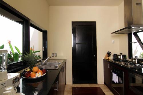 a kitchen with a black door and a bowl of fruit at Temple Hill Residence Villa in Jimbaran