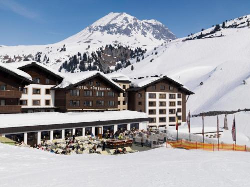 een skilodge tegenover een met sneeuw bedekte berg bij Hotel Zürserhof in Zürs am Arlberg