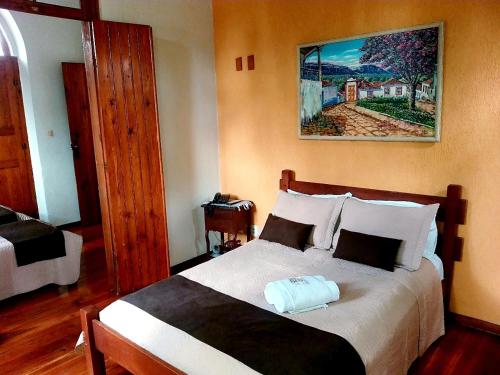 a bedroom with a bed and a painting on the wall at Pousada Estação do Trem in São João del Rei