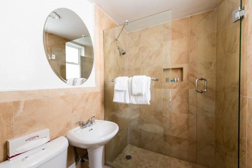 ein Bad mit einer Dusche, einem Waschbecken und einem Spiegel in der Unterkunft Majestic Hotel South Beach, Trademark Collection by Wyndham in Miami Beach