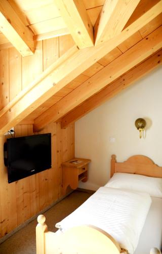 Un dormitorio con una cama y un televisor de pantalla plana. en Casa Tödi Restaurant Hotel, en Trun