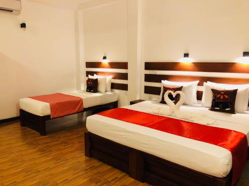 a bedroom with two beds with red and white sheets at Villa Angel in Hikkaduwa