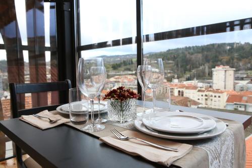 a table with glasses and plates on a table with a view at Muralha Charm House in Lamego