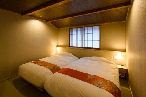 a large bed in a room with a window at The Besso Soso Kyoto in Kyoto