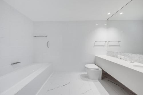 a white bathroom with a toilet and a sink at Vibe Hotel Sydney in Sydney