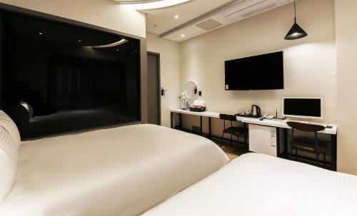 two beds in a room with a desk and a television at If Business Hotel in Changwon