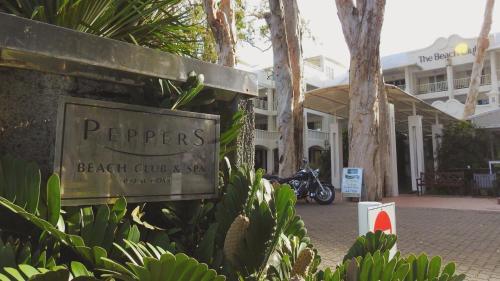 a sign for a beach club and a building at Palm Cove Paradise - Couples spa beach getaway in Palm Cove