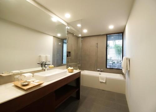 a bathroom with a sink and a mirror and a tub at Penh House Hotel in Phnom Penh