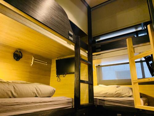 two bunk beds in a room with a tv at WORK INN TPE in Taipei