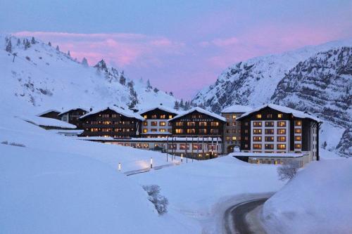 a hotel in the snow with snow covered mountains at Hotel Zürserhof in Zürs am Arlberg