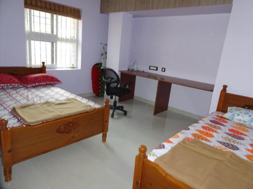 1 dormitorio con 2 camas y escritorio en Haritham en Tiruchchirāppalli