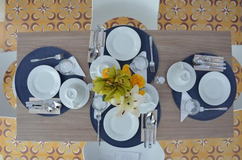 a table with white plates and a vase of flowers at Villaviciosa Hotel Boutique in Pasto