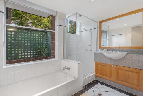 a bathroom with a tub and a sink and a mirror at Airport International Motel Brisbane in Brisbane