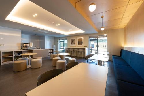 a room with tables and chairs and a kitchen at Browndot Business Seomyeon in Busan