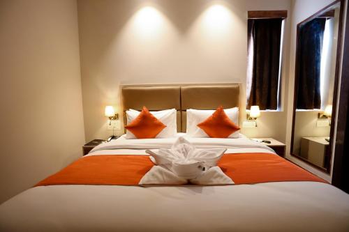 a bedroom with a large bed with orange and white pillows at Calux Grand Baga - Formerly Amara Grand in Baga
