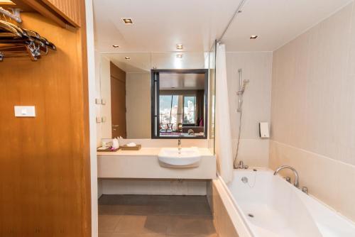 ein Badezimmer mit einem Waschbecken, einer Badewanne und einem Spiegel in der Unterkunft ASHLEE Hub Hotel Patong in Patong Beach
