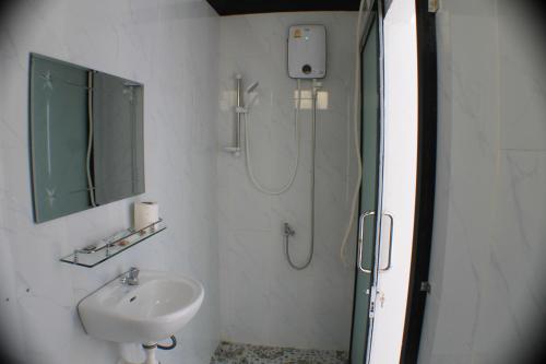 een badkamer met een wastafel en een douche met een spiegel bij Sofinny Motel in Sihanoukville