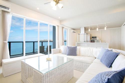 a living room with a white couch and a glass table at Costa Bella Condominium Resort in Motobu