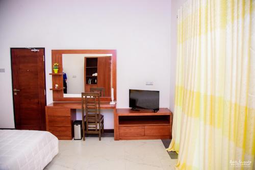 a bedroom with a bed and a desk with a television at Cogent Holiday Home in Gelioya