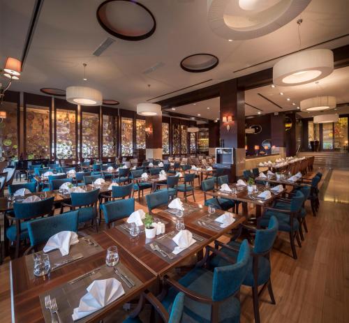 un restaurante con mesas de madera y sillas azules en Titanic Business Kartal en Estambul