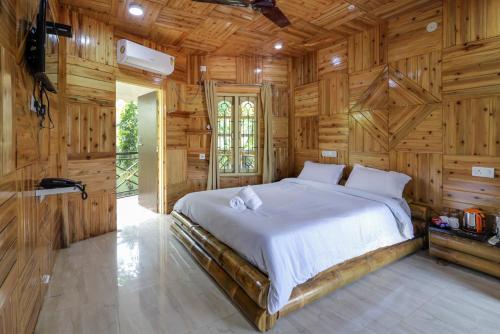 a bedroom with a large bed in a wooden wall at Resort Trimurti in Chālsa Mahābāri