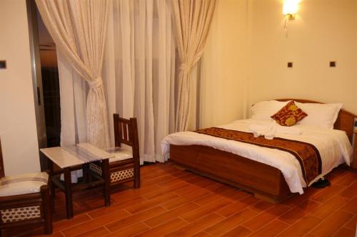 a bedroom with a bed and a table and a chair at Tabor Hotel Lalibela in Lalībela